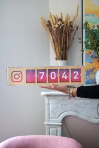 a woman holding up a wooden block with numbers on it