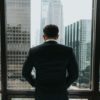 man putting hands on pocket while standing in front of glass wall